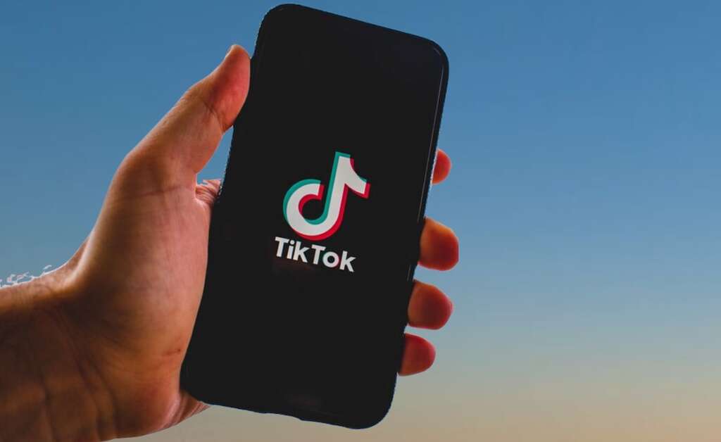 Hand holding a smartphone with TikTok logo