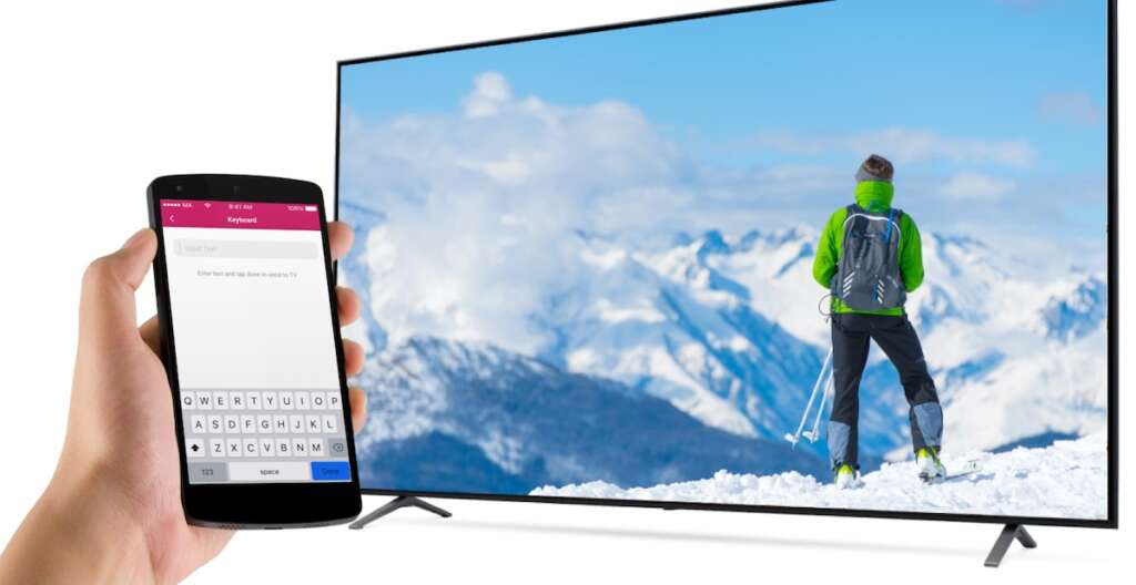 LG TV with an image of a man on a snowy mountain summit. A hand holding an Android phone with LG tV Remote APp Keyboard feature on the screen