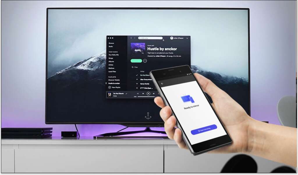 A hand holding an Android smartphone with the MirrorMeister connect to TV screen. A samsung tv with spotify on the screen