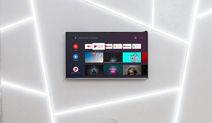 Wall-mounted TV with Google TV interface on the screen.